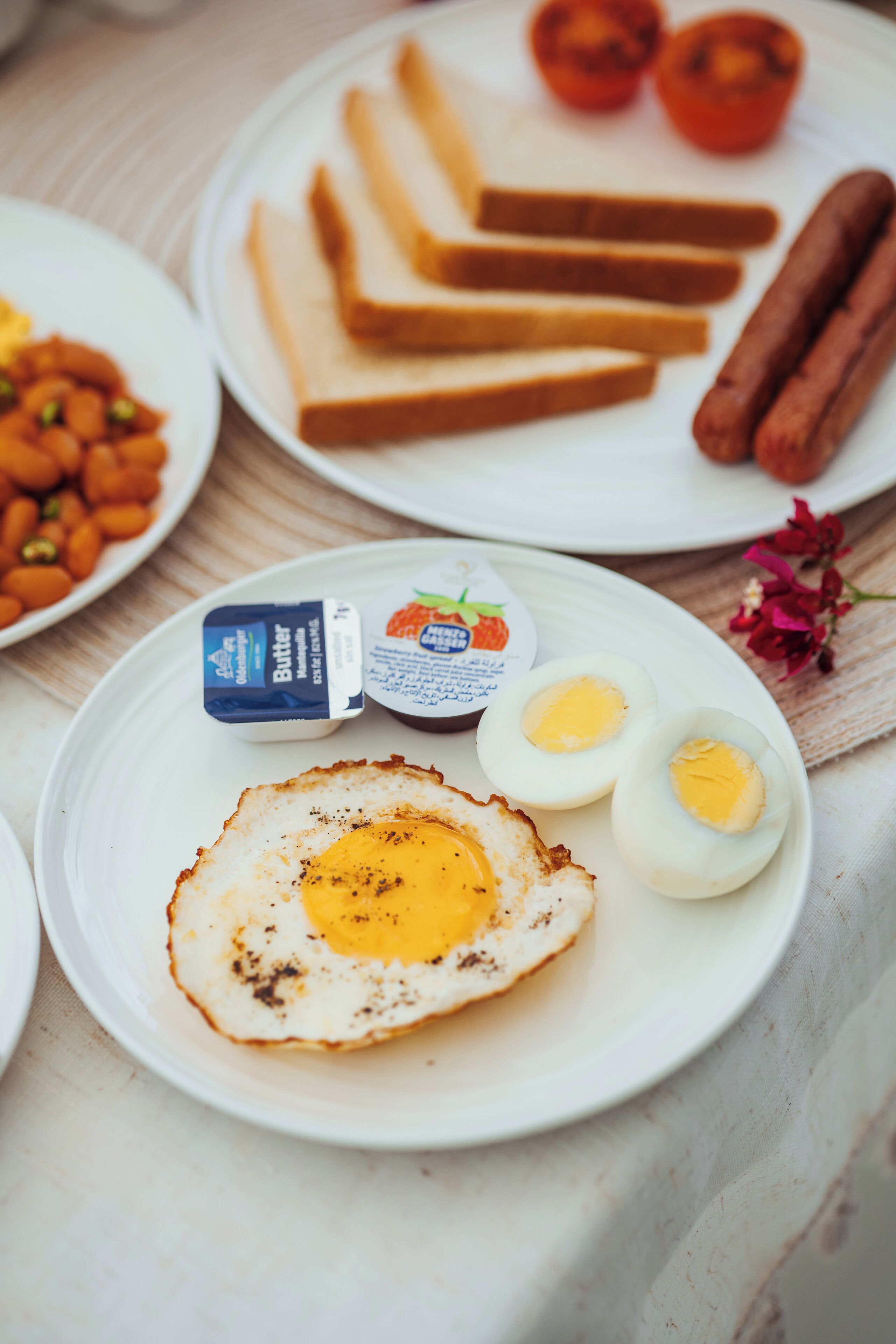A breakfast plate with fried eggs, toast, sausages, and tomatoes.