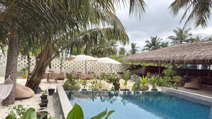 Un espace piscine aménagé avec des chaises longues, un hamac et des plantes en pot.