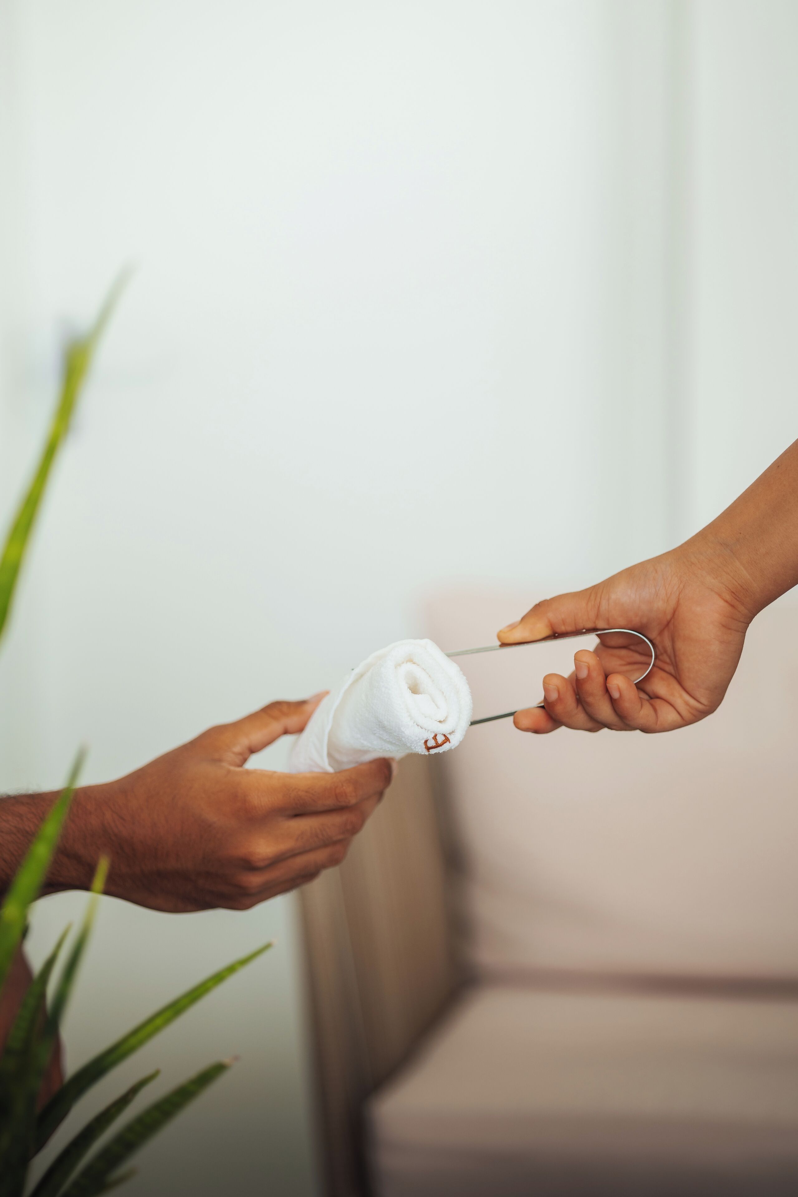 A hand holding a white object with a metal clip, possibly a bottle or container, against a neutral background.