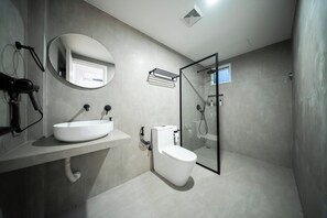 Ein modernes Badezimmer mit einem großen Waschbecken, Toilette und einer Duschkabine aus Glas.