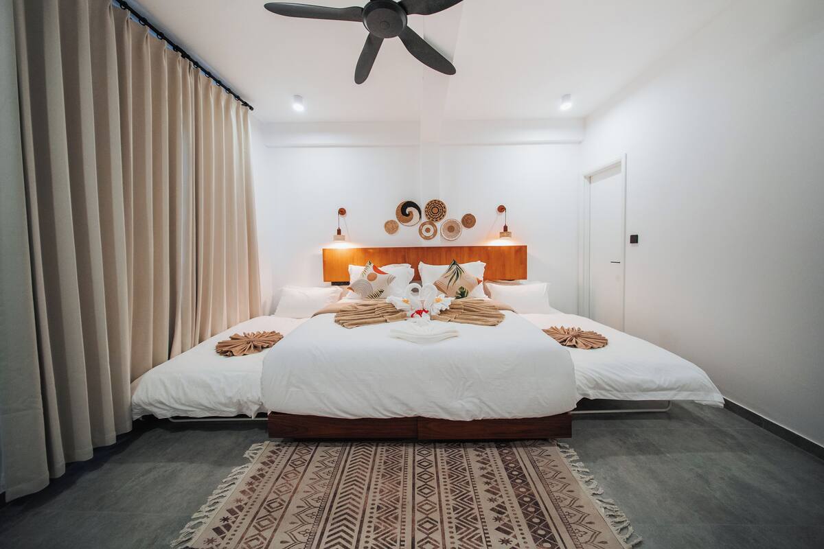 A modern hotel room with a large bed, a ceiling fan, and a patterned rug.