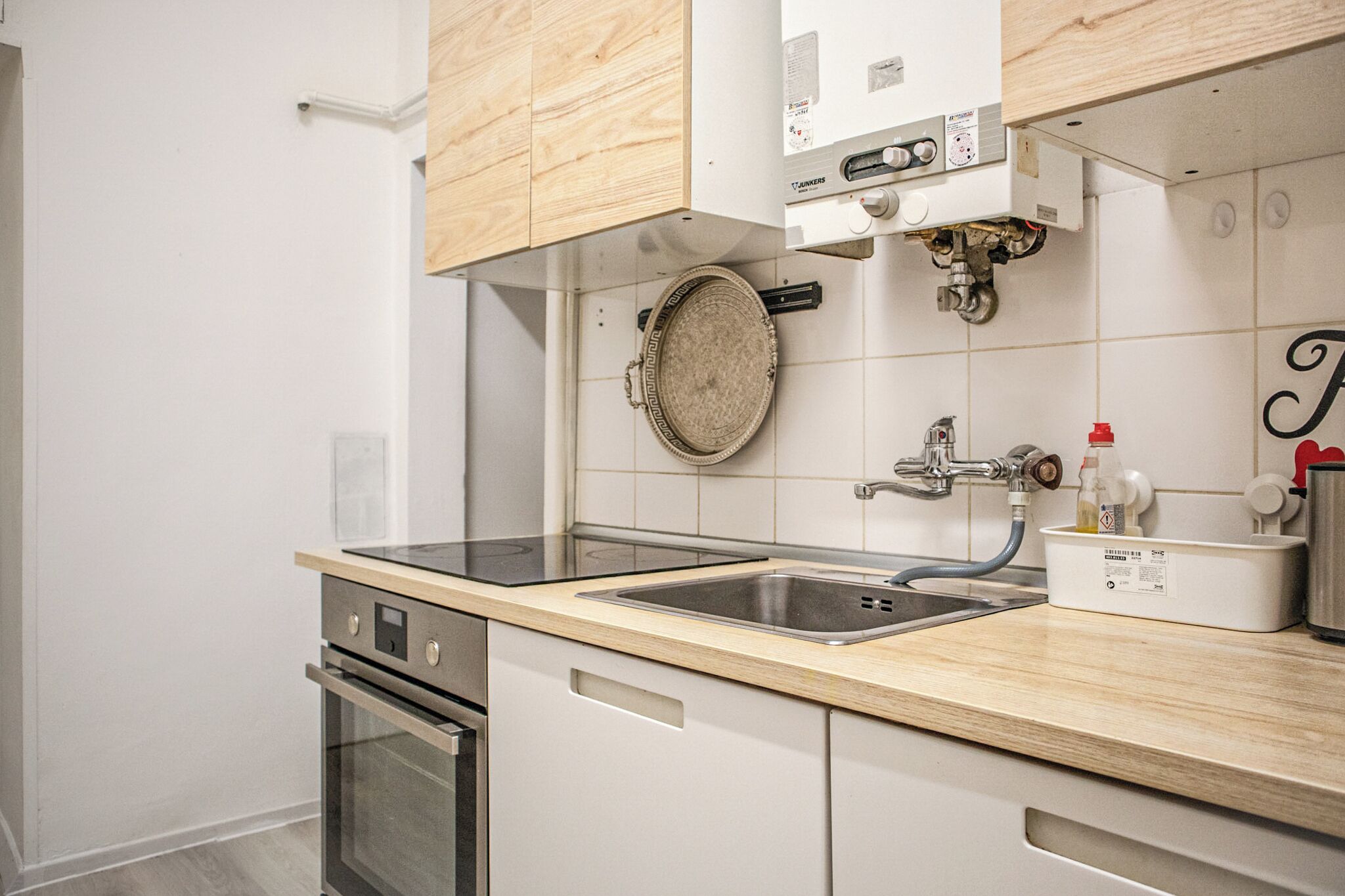 A modern kitchen with a built-in oven, a stovetop, a sink, and a range hood.