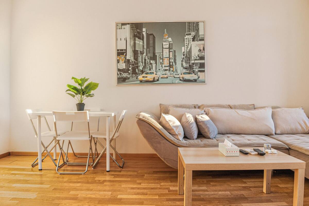 A living room with a sofa, a coffee table, and a dining area with chairs and a table.