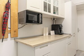 Compact kitchen with microwave, coffee maker, and storage.
