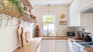 A modern kitchen with white cabinets, a wooden countertop, a gas stove, and a microwave. - Charming Lakeside 2-bedroom cottage in lovely Alburgh, VT (Alburgh)