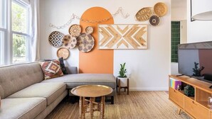 A living room with a sofa, a coffee table, a TV, and decorative wall art. - Charming Lakeside 2-bedroom cottage in lovely Alburgh, VT (Alburgh)