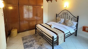 Een slaapkamer met een bed, een houten garderobe en een plafond met zichtbare balken.