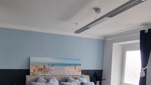 A bedroom with a bed, a nightstand, a lamp, a painting, and a window with curtains.