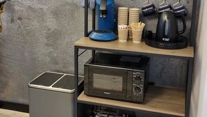 A kitchen with a coffee machine, a microwave, and a shelf with kitchenware. - Vacation apartment in prime location on the Moselle with balcony & garden. (Brauneberg)