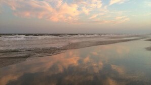 A beach with calm waters reflecting the sky. - Relax in Style Oceanview Villa w/ Resort Amenities & Steps to the Beach (Ocean Isle Beach)