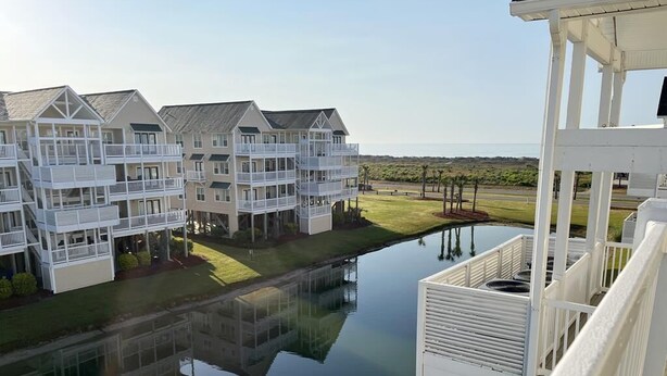 A waterfront residential building with multiple balconies, a dock, and a clear view of the ocean. - Relax in Style Oceanview Villa w/ Resort Amenities & Steps to the Beach (Ocean Isle Beach)