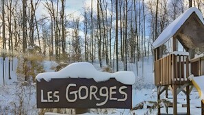 Un letrero de madera indica 'LES GORGES' y 'WINDIGO', con un bosque nevado de fondo.