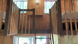 Un interior de madera con literas, una ventana y una lámpara.