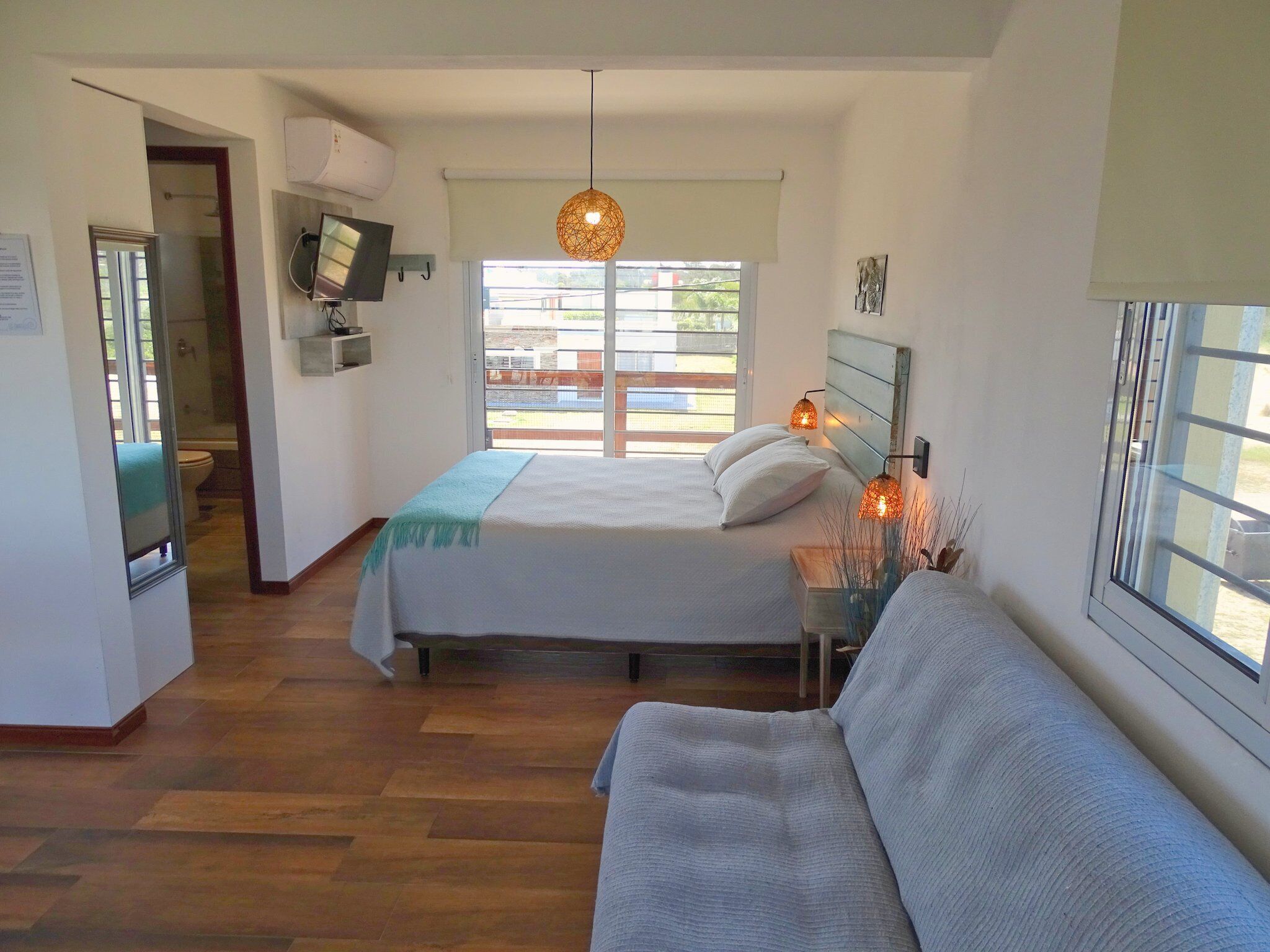 A bedroom with a bed, a sofa, a TV, and a window with a view.