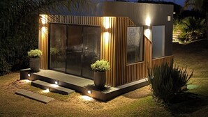 A modern, well-lit structure with a glass facade, wooden paneling, and two potted plants. - Los Caracoles (Punta del Diablo)