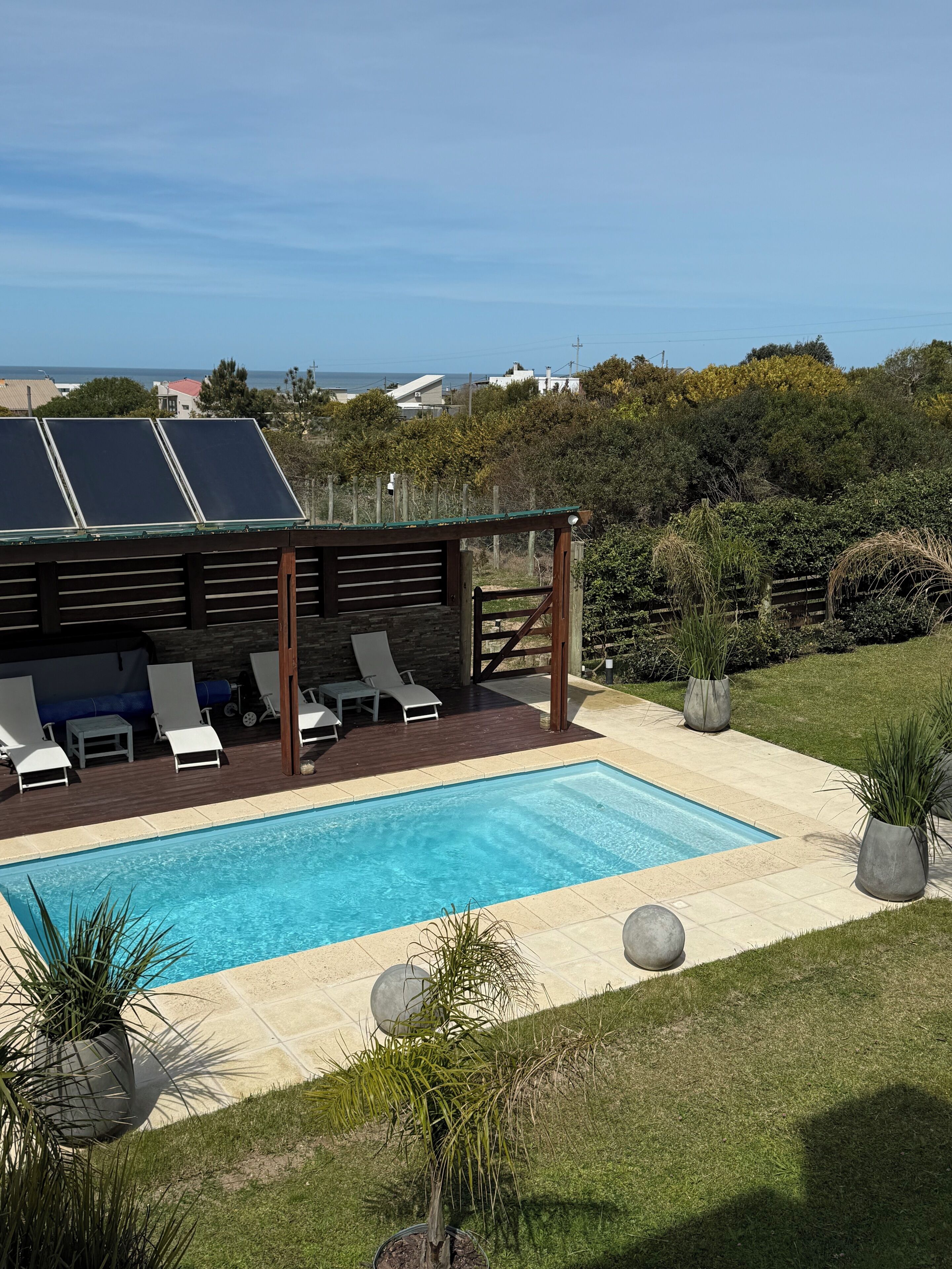 Una piscina con sillas de descanso, una pérgola y paneles solares.
