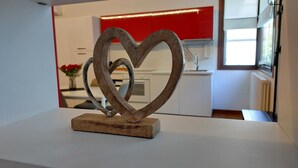 A heart-shaped metal sculpture on a wooden base in a modern kitchen with white cabinets and a red backsplash. - Villa Anna, apartment no. 2 (Venezia)