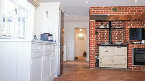 A kitchen with white cabinetry, a brick wall, and a tiled floor. - Holm Oak Lodge (Clacton-on-Sea)