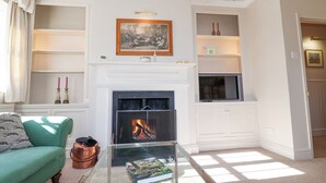 A living room with a fireplace, a sofa, a coffee table with a book, and a television. - Holm Oak Lodge (Clacton-on-Sea)