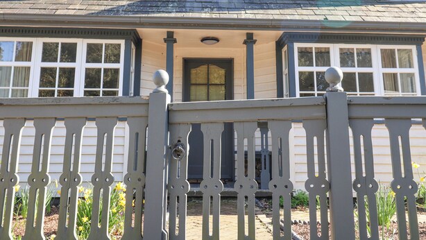 A two-story house with a front porch, a picket fence, and a chimney. - Holm Oak Lodge (Clacton-on-Sea)