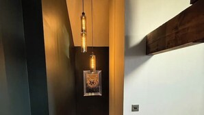 Een trap met een donkere muur, een houten balk en een hangende lamp.
