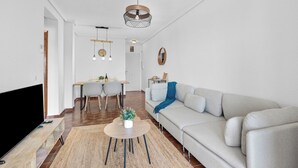 A modern living room with a sofa, a coffee table, a TV, and a dining area with a table and chairs.