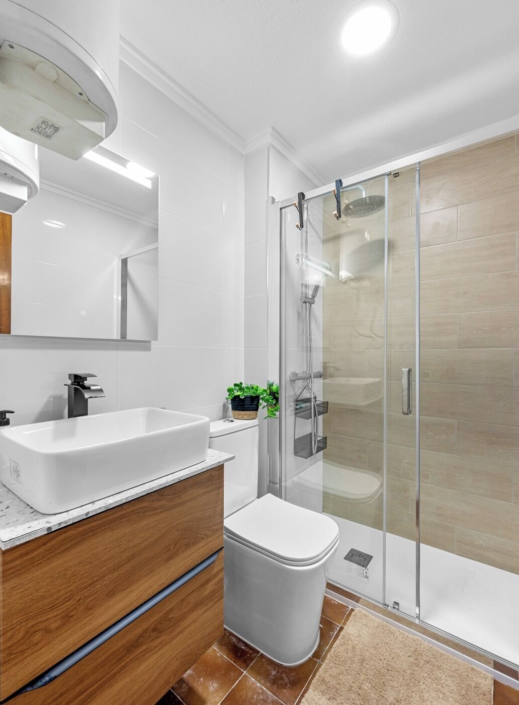 Une salle de bain moderne avec un lavabo blanc, un meuble-lavabo en bois, des toilettes et une douche à parois de verre.