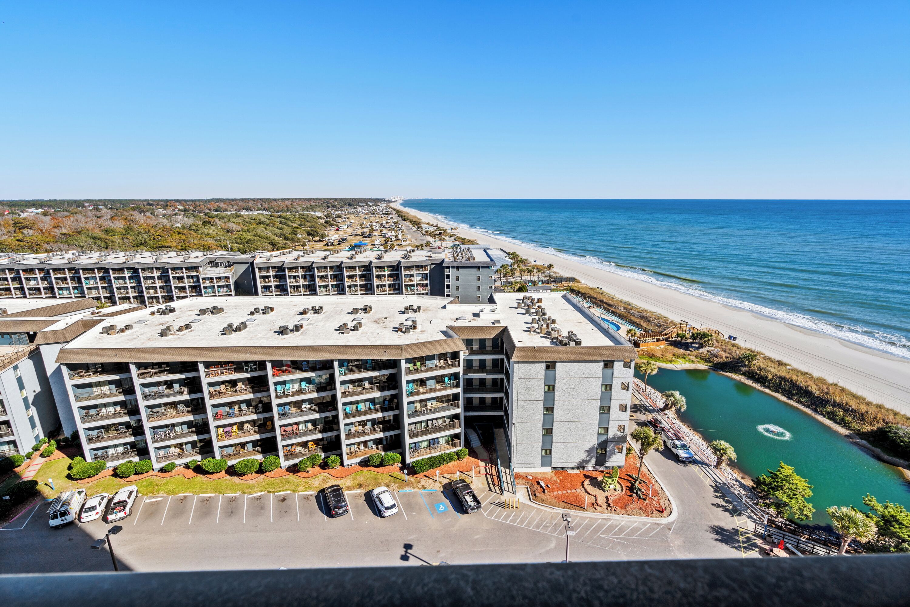 Ein mehrstöckiges Hotel mit Parkplatz und Blick auf den Strand.