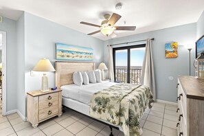 A bedroom with a bed, a nightstand, a ceiling fan, a window with curtains, and a painting on the wall. - Myrtle Beach Resort RT2111 (Myrtle Beach)