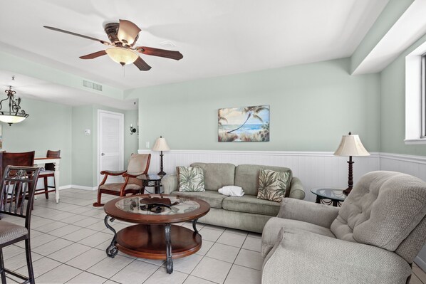 A living room with a ceiling fan, a coffee table, a sofa, and a painting on the wall. - Myrtle Beach Resort RT2111 (Myrtle Beach)