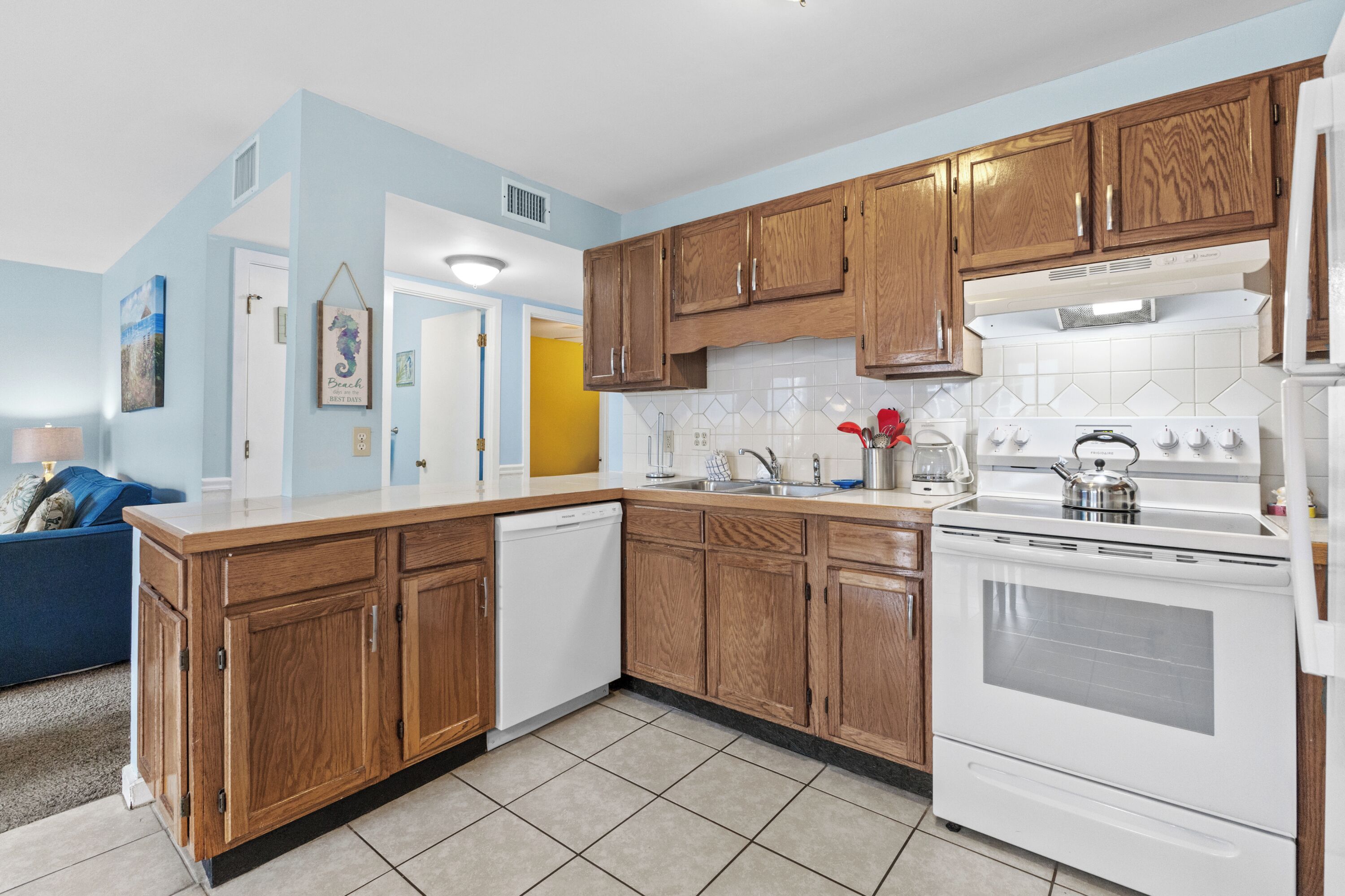 A kitchen with wooden cabinets, a white stove, and a dishwasher.