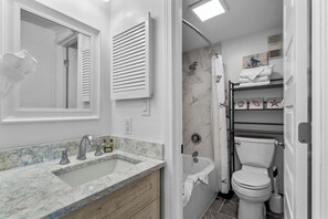 Une salle de bain avec un lavabo en marbre, des toilettes, une douche et un porte-serviettes.