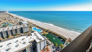 Ein Küstenhotel mit Blick auf den Strand, einem Swimmingpool und einem Parkplatz.