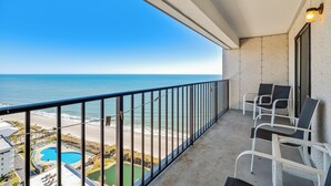 Ein Balkon mit Blick auf den Ozean und einen Poolbereich.
