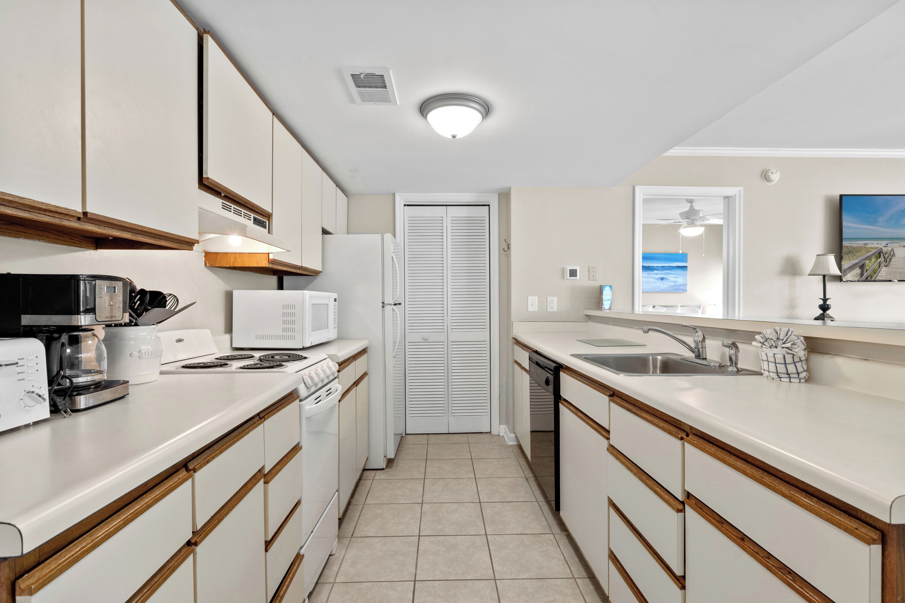 A modern kitchen with white appliances, wooden cabinets, and a tiled floor.