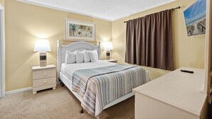 A hotel room with a bed, two bedside lamps, a nightstand, a desk, a brown curtain, and a framed picture on the wall. - 2 BR 2 Bath Condo | Myrtle Beach Resort A0348 (Myrtle Beach)