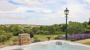 A hot tub with a view of a countryside landscape, a stone structure, and a lamp post. - New Elms Farmhouse (Derby)