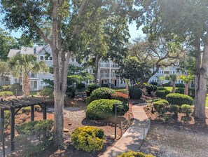 A courtyard with a wooden pergola, a pathway, and a building with multiple balconies. - Myrtle Beach Resort FS4204 (Myrtle Beach)