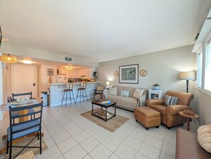 A living room with a sofa, ottoman, coffee table, and a dining area with chairs and a table. - Myrtle Beach Resort FS4204 (Myrtle Beach)
