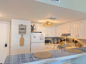 A modern kitchen with white cabinets, a built-in microwave, a stainless steel range, and a hanging light fixture.