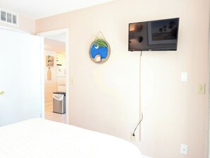 A room with a bed, a TV mounted on the wall, a trash bin, and a door leading to another room. - Myrtle Beach Resort FS4204 (Myrtle Beach)