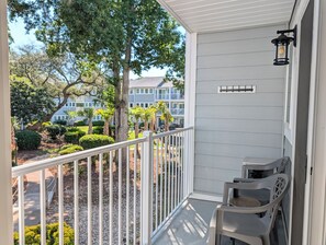 A balcony with a railing, a table with chairs, and a view of a building with a balcony. - Myrtle Beach Resort FS4204 (Myrtle Beach)