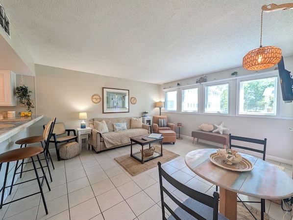 A modern living room with a sofa, chairs, a coffee table, and a dining table.