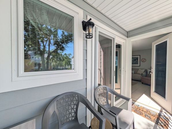 A covered porch with a sliding glass door leading to an interior living space.