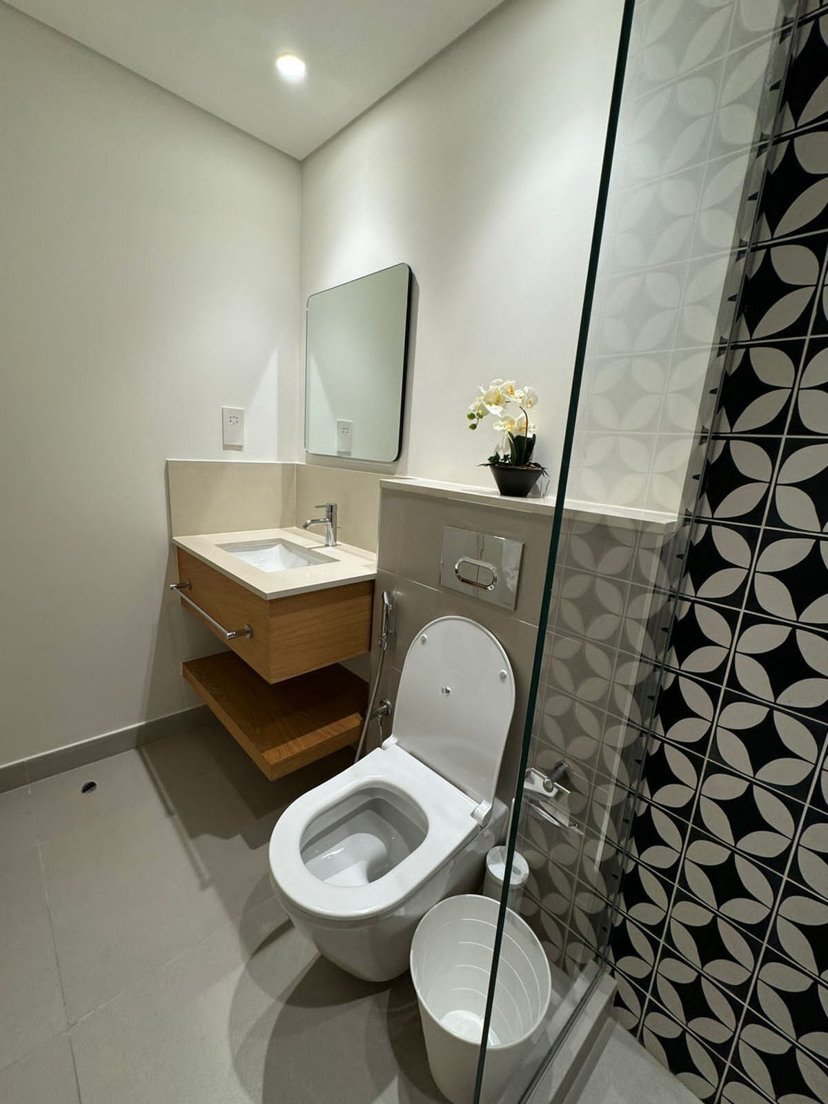 A modern bathroom with a toilet, sink, and mirror.
