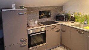 Une cuisine moderne équipée d’un four à micro-ondes encastré, d’un four traditionnel et d’une machine à café posée sur le plan de travail.