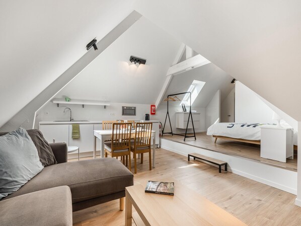 Un loft moderno con comedor, sofá y una pequeña mesa.