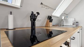 A modern kitchen with a black countertop, a coffee machine, and utensils hanging on the wall.