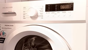 A front-loading washing machine with a digital display, a control panel, and a patterned floor.