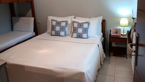 A bedroom with two single beds, a nightstand with a lamp, and a small table with a picture.